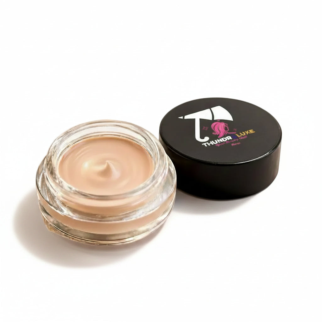 Cosmetic cream jar with black lid featuring a brand logo, surrounded by white flowers on a light background.